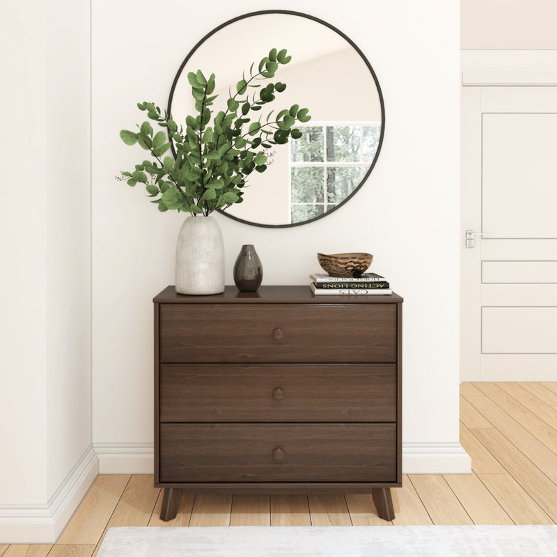 Modern wooden dresser with decorative mirror and potted plant in a minimalist room.
