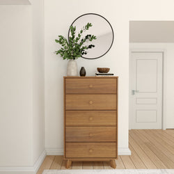 Wooden dresser with circular mirror and decorative plants in a modern, minimalist room setting.