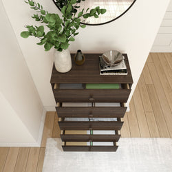 Dark wood dresser with open drawers, decorated with plants and modern accessories, in a stylish bedroom setting.