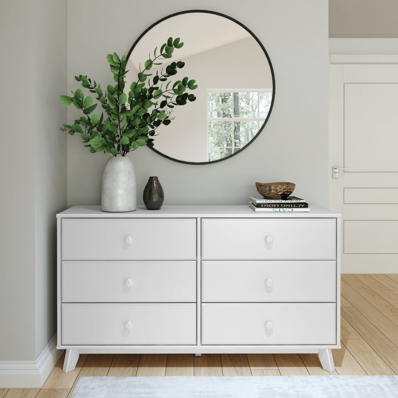 Modern white dresser with round mirror and decorative plants in a stylish minimalistic bedroom setup.