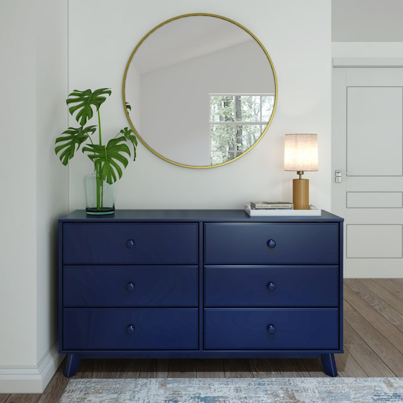 Blue dresser with round mirror, houseplant, and lamp in a modern room interior.