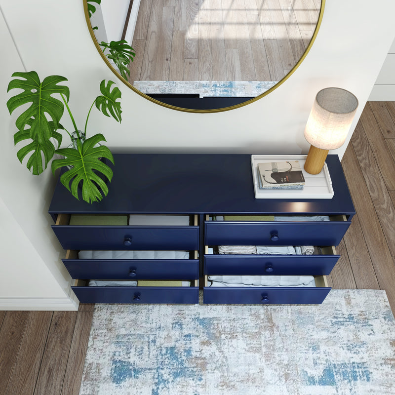 Navy blue dresser with open drawers, a modern lamp, and a mirror in a stylish, minimalist bedroom setting.