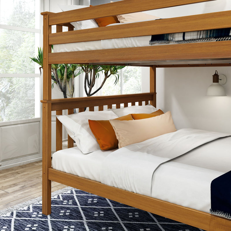 Wooden bunk bed frame with white bedding and orange pillows in a bright room with a large window and blue geometric rug.