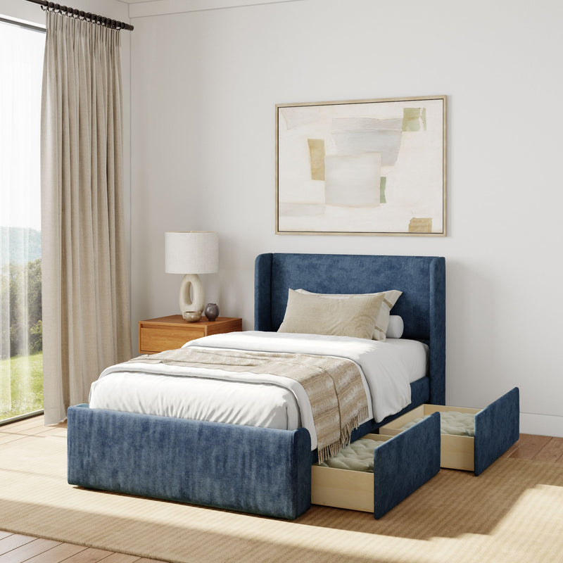 Blue upholstered storage bed with bedding, wooden nightstand, lamp, and abstract wall art in a stylish bedroom.