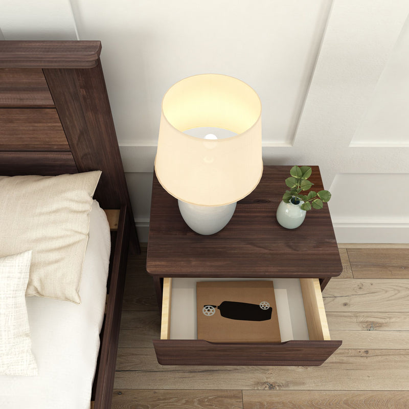 Cozy bedroom setting with a wooden nightstand, table lamp, and a small plant in a vase.