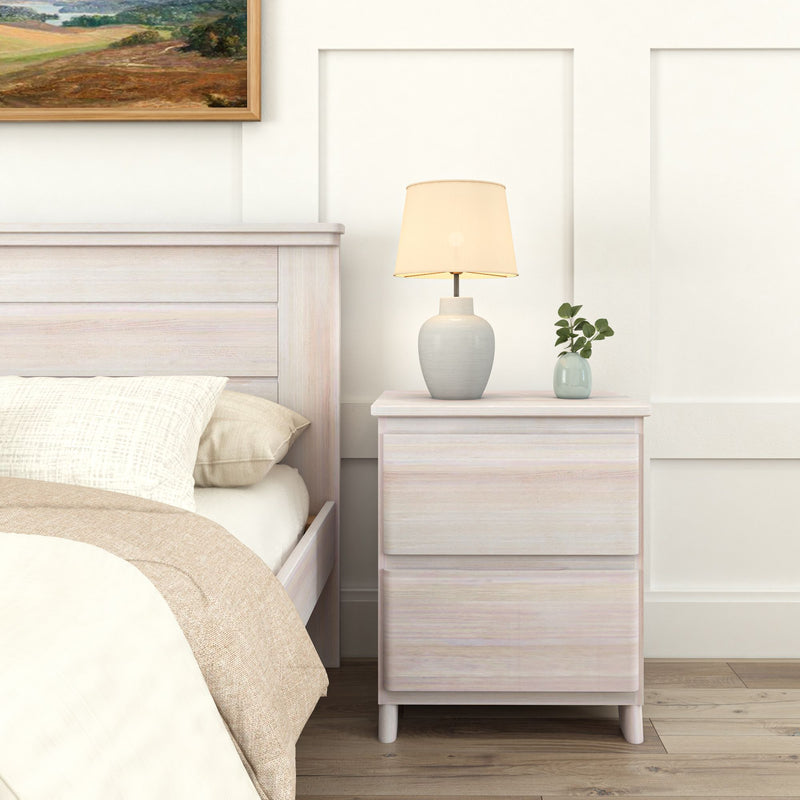 Bedroom with white wooden nightstand, table lamp, and minimalistic decor next to a cozy bed.