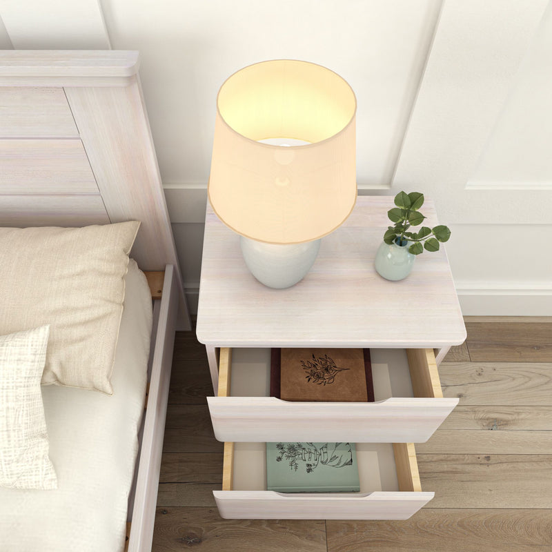 Bedroom nightstand with lamp, open drawers containing books, and a small plant on top.