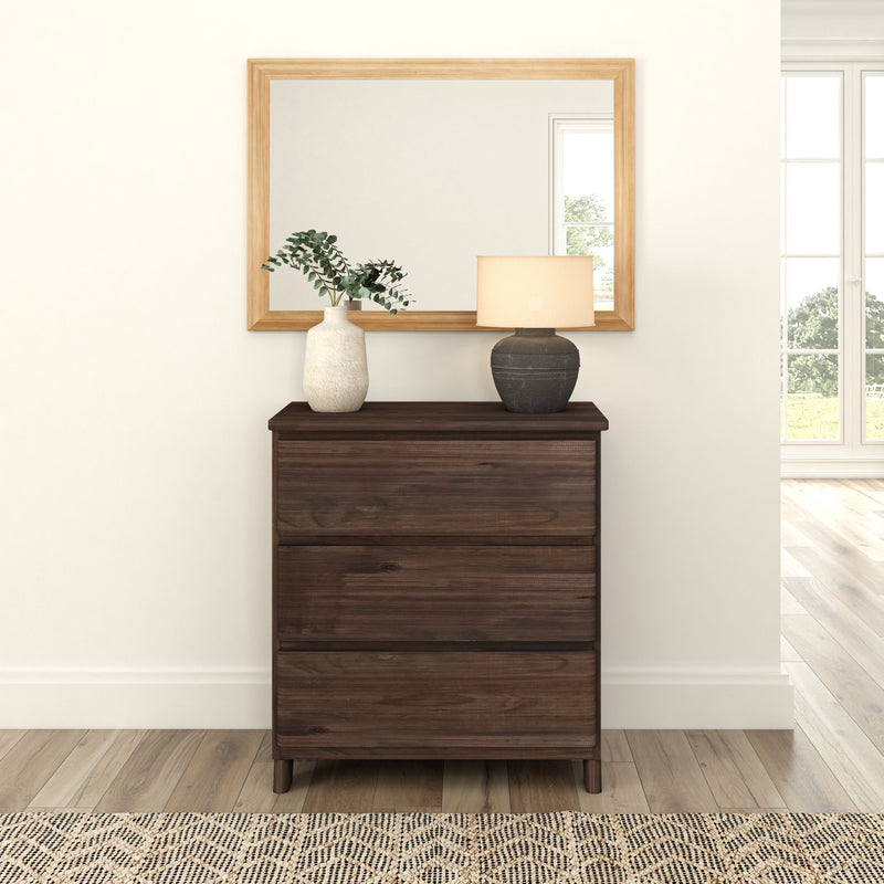 Modern wooden dresser with decorative vase and lamp against a large mirror in a bright, minimalist room.