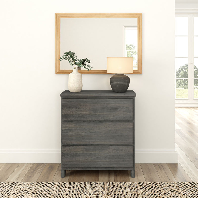 Dark wood dresser with decorative vase and lamp against white wall with framed mirror.