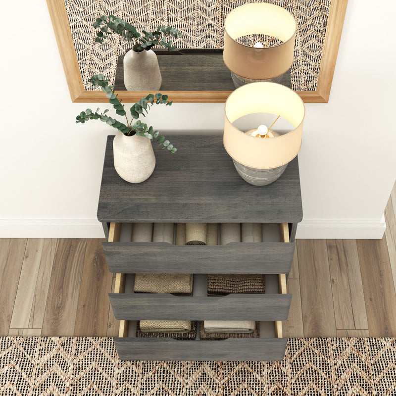 Modern bedroom dresser with open drawers, decorative vase, and table lamp on wooden floor.