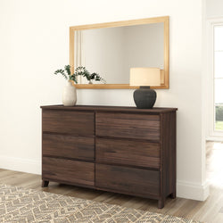 Dark walnut dresser with wood-framed mirror, ceramic vase of eucalyptus and table lamp in minimalist bedroom interior