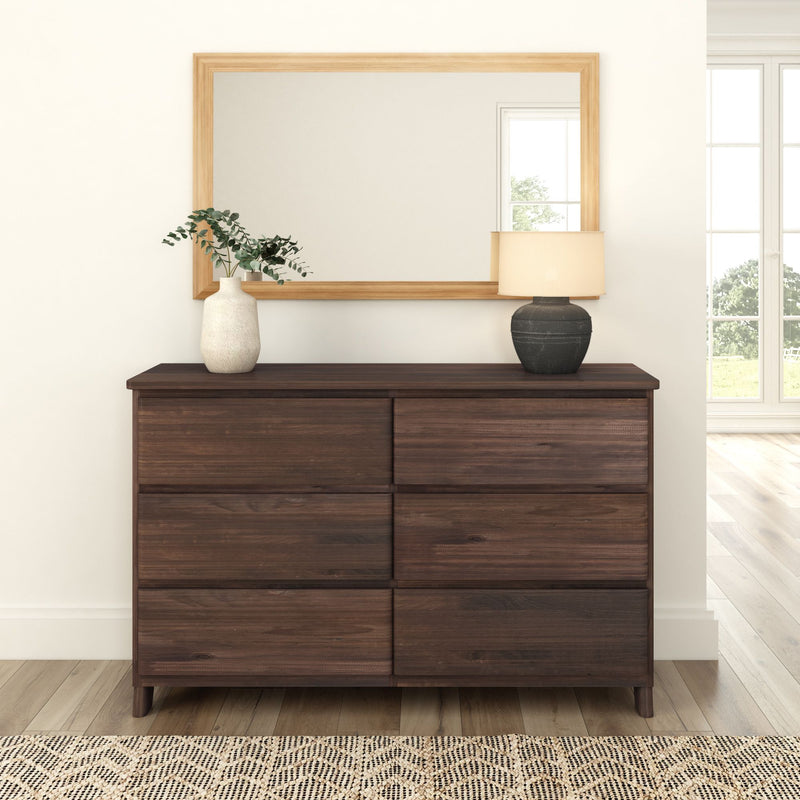 Modern dark wood dresser with decorative vases and lamp in bright interior.
