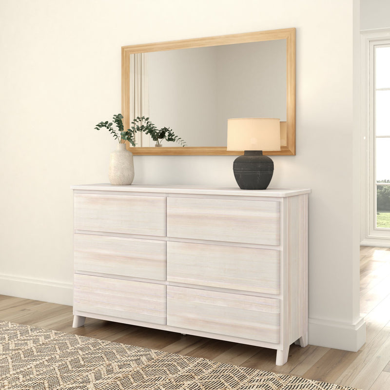 White wooden dresser with six drawers, decorative mirror, and vases in a modern bedroom setting.