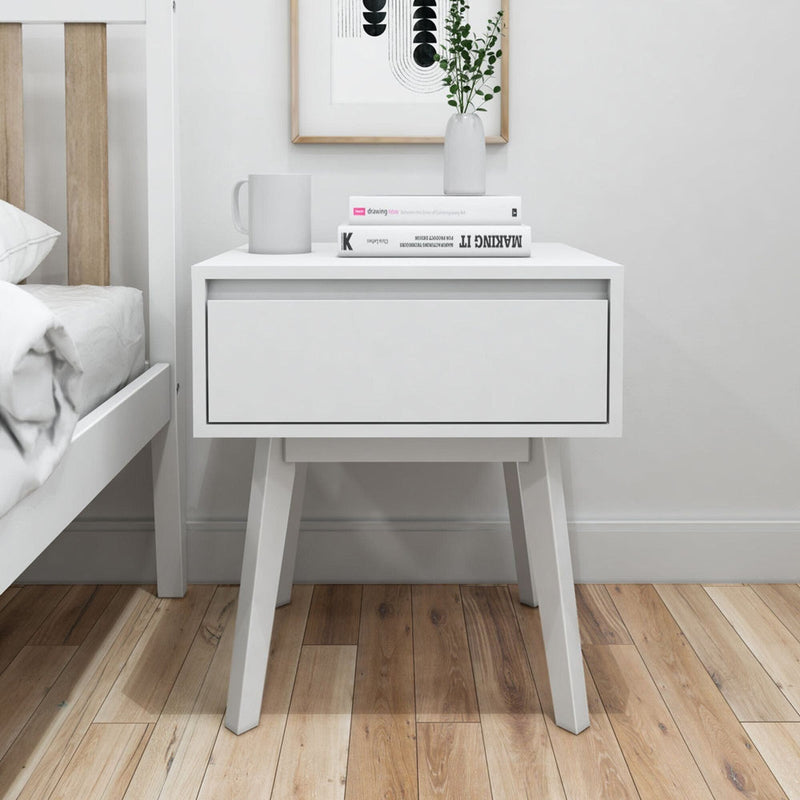 Modern white wooden nightstand with books and decor in minimalistic bedroom.