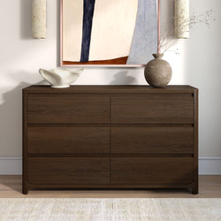 Dark walnut dresser with minimalist home decor — white sculptural bowl, textured round vase with dried branches, abstract framed art and wall sconces