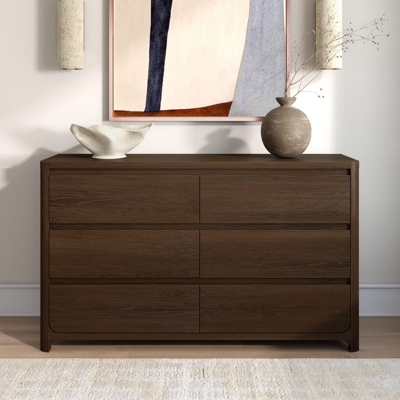 Dark walnut dresser with minimalist home decor — white sculptural bowl, textured round vase with dried branches, abstract framed art and wall sconces