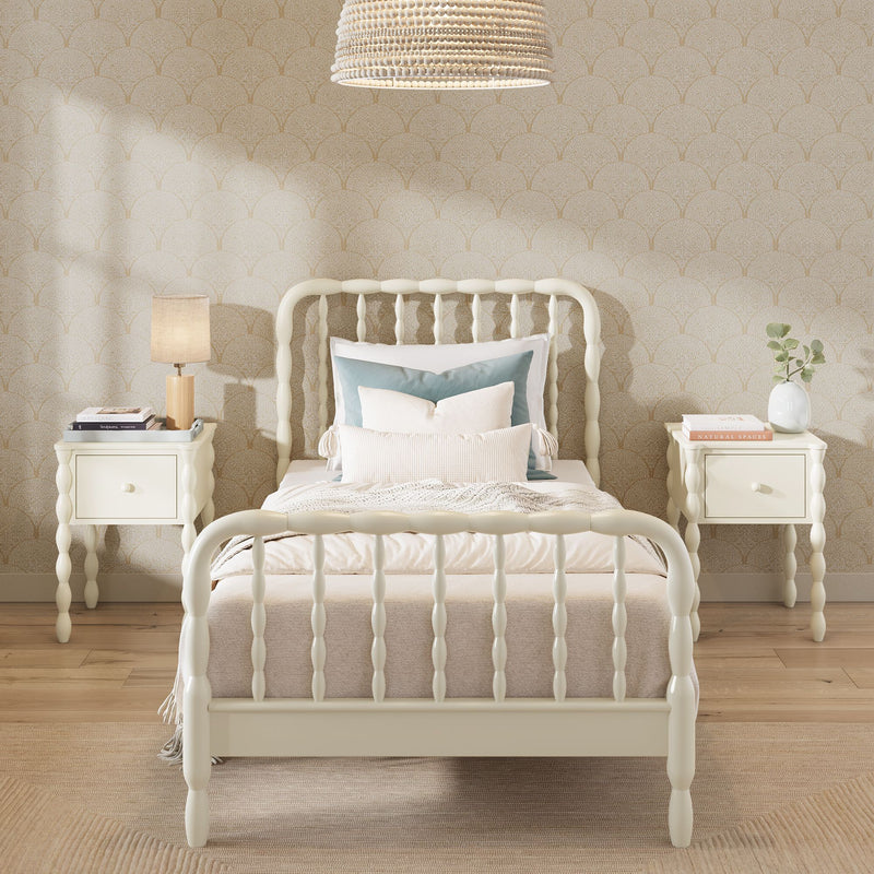 Cream spindle twin bed with layered neutral bedding, matching nightstands, rattan pendant light and scallop-pattern wallpaper in a cozy modern farmhouse bedroom interior design