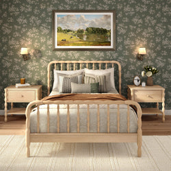 Cozy farmhouse bedroom interior with light wood spindle bed, green floral wallpaper, neutral bedding, matching nightstands, wall lamps and framed landscape art