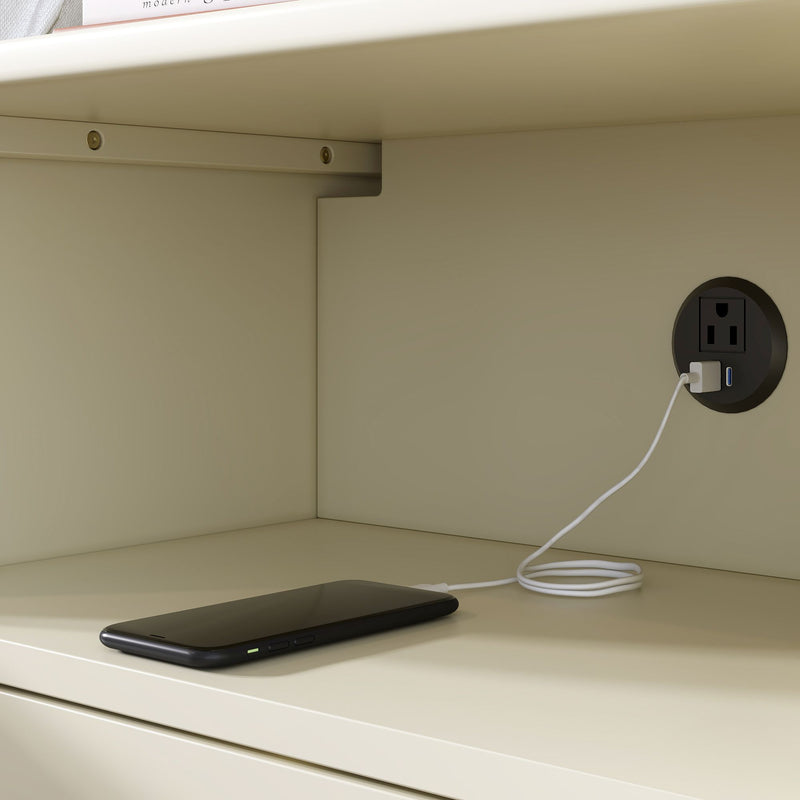 Black smartphone charging on a beige cabinet shelf, white USB cable plugged into a round recessed outlet with built-in USB port