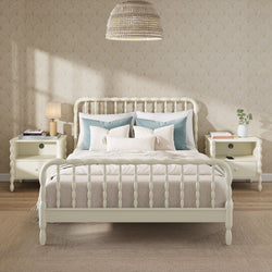 Cozy modern farmhouse bedroom with cream spindle bed, layered beige bedding and blue accent pillows, matching cream nightstands, woven pendant light and subtle beige patterned wallpaper