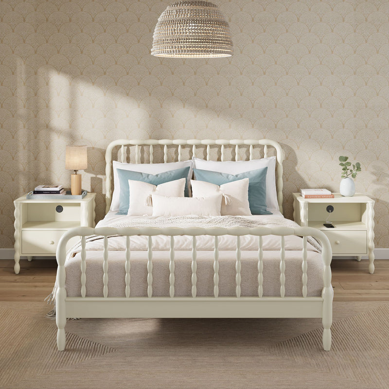 Cozy modern farmhouse bedroom with cream spindle bed, layered beige bedding and blue accent pillows, matching cream nightstands, woven pendant light and subtle beige patterned wallpaper