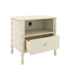 Cream wooden nightstand with turned spindle legs, open cubby shelf, single pull-out drawer showing wood interior and built-in power outlet