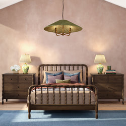 Cozy modern farmhouse bedroom with wooden spindle bed, matching dark wood nightstands, floral table lamps, pastel pink wall and blue area rug