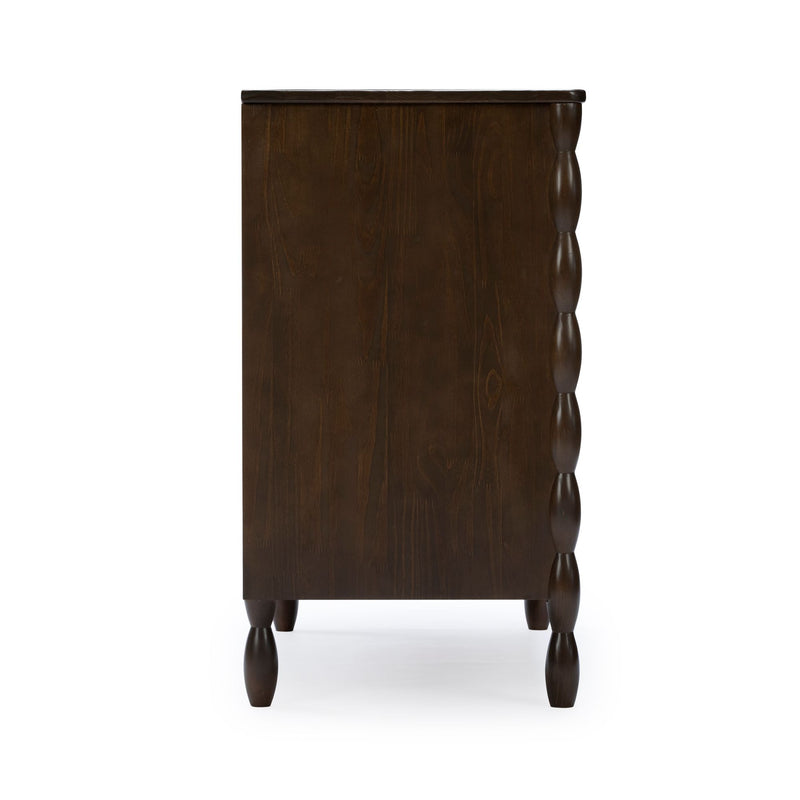 Dark brown wooden dresser side view with turned spindle legs and carved scalloped side detail, rustic farmhouse bedroom chest