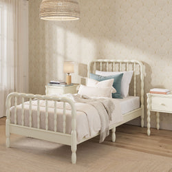 Cream spindle bed with turned legs and matching nightstands in a cozy neutral bedroom — textured wallpaper, layered linens, woven pendant light, farmhouse cottage decor