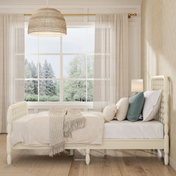 Cozy neutral bedroom with tufted cream bed, knit throw blanket, layered pillows, rattan pendant light and large window with tree view