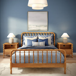 Coastal blue bedroom with wooden spindle bed, navy and white bedding, matching nightstands and lamps, and framed seascape wall art.