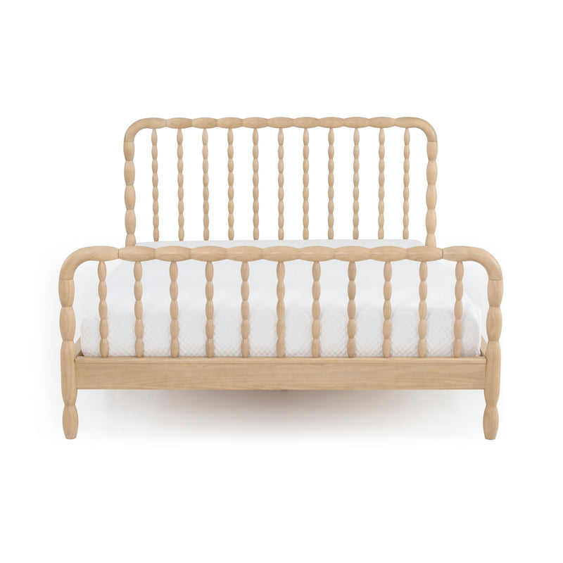 Front view of a natural light-wood spindle bed frame with turned posts, curved headboard and footboard, and white mattress — farmhouse-style wooden bed