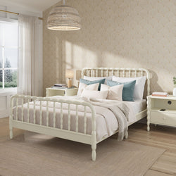 Cream spindle bed with neutral linen bedding and blue accent pillows in a bright farmhouse bedroom with scallop-pattern wallpaper, woven pendant light, matching nightstands and sheer-curtain window