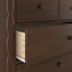 Close-up of dark walnut dresser with partially open drawer revealing dovetail joinery, round wooden knob and carved vertical post — solid wood bedroom storage furniture