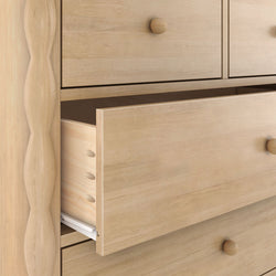 Close-up of solid light wood dresser drawers with an open drawer, visible dovetail joints and round wooden knobs