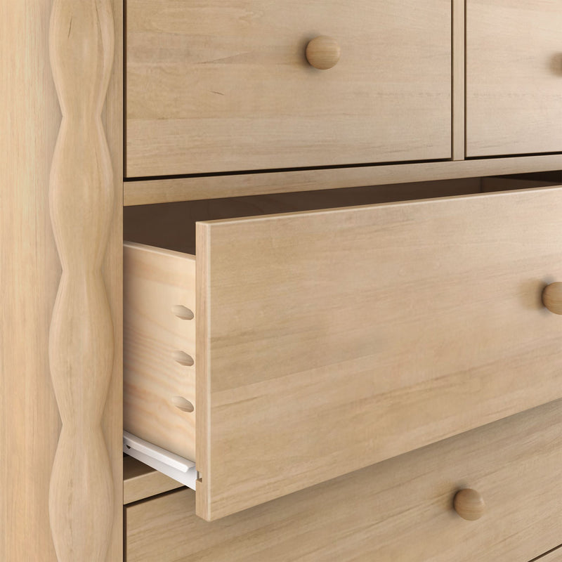 Close-up of solid light wood dresser drawers with an open drawer, visible dovetail joints and round wooden knobs
