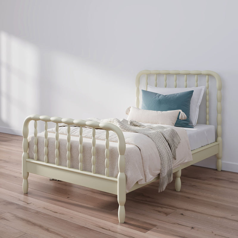Minimalist bedroom with cream spindle bed frame, white bedding, blue accent pillow, knitted throw blanket and hardwood floor
