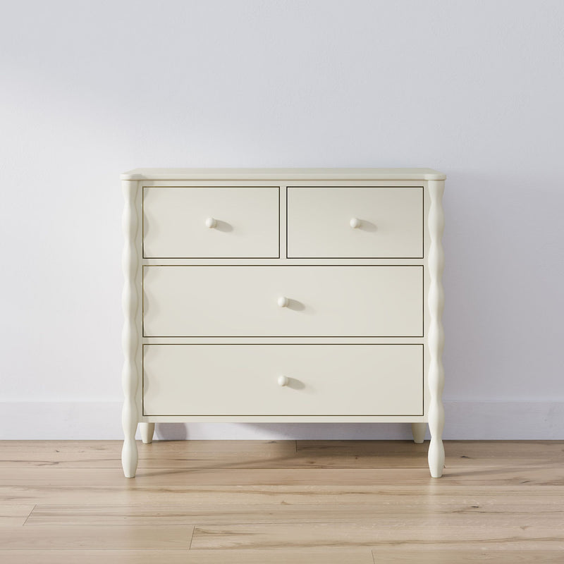 Cream wooden chest of drawers dresser with round knobs on light hardwood floor against a white wall, minimalist bedroom storage furniture