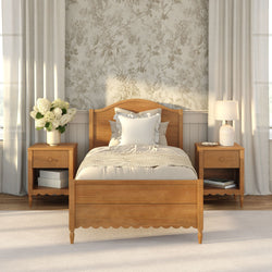 Cozy farmhouse bedroom with wooden bed frame and matching nightstands, neutral bedding, floral wallpaper, table lamp and white hydrangea bouquet in natural light