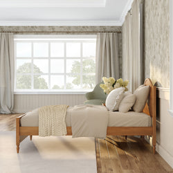 Cozy neutral bedroom with wooden bed frame, beige bedding and knit throw, large grid window with sheer curtains and natural light, green accent chair with white flower bouquet, floral wallpaper and hardwood floors