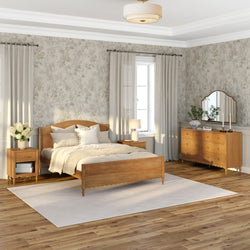 Cozy neutral bedroom with wooden bed frame, matching dresser and nightstands, soft beige bedding and throw, floral wallpaper, large window with curtains, hardwood floors and white area rug, lamp and mirror — modern farmhouse bedroom decor with natural light