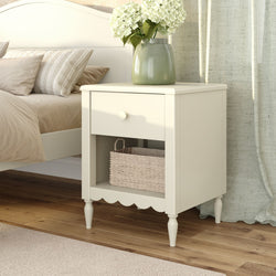 Cream white bedside table nightstand with drawer, wicker basket and green vase of white hydrangeas in cozy neutral bedroom decor
