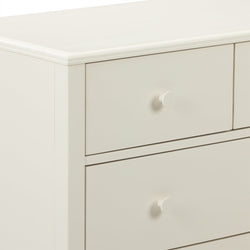 Close-up of cream white wooden dresser drawers with round knob and smooth beveled top, modern nursery bedroom storage cabinet
