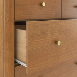 Wooden dresser drawer partially open with brass knob, dovetail joints and metal drawer slides, modern bedroom storage furniture