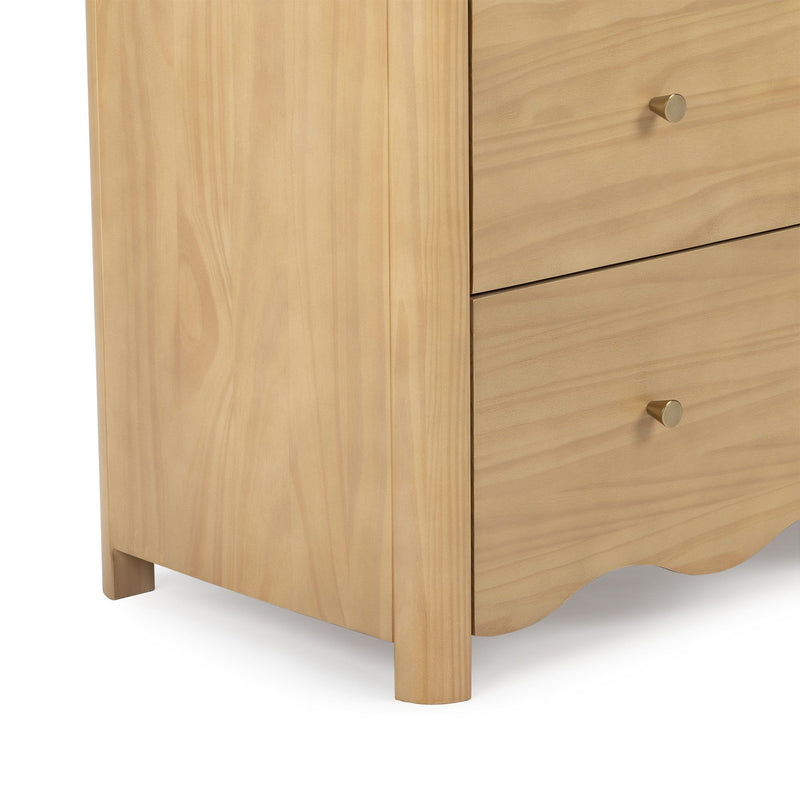 Close-up of light maple wood nightstand drawers with round brass knobs and scalloped base