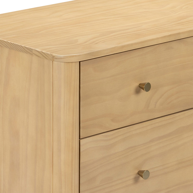 Close-up of light pine dresser drawers with natural wood grain, rounded top edge and brass knob