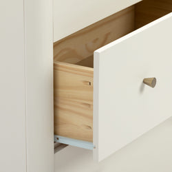 Minimalist white dresser drawer partially open revealing natural wood interior, brass cone knob and metal slide — modern bedroom storage detail