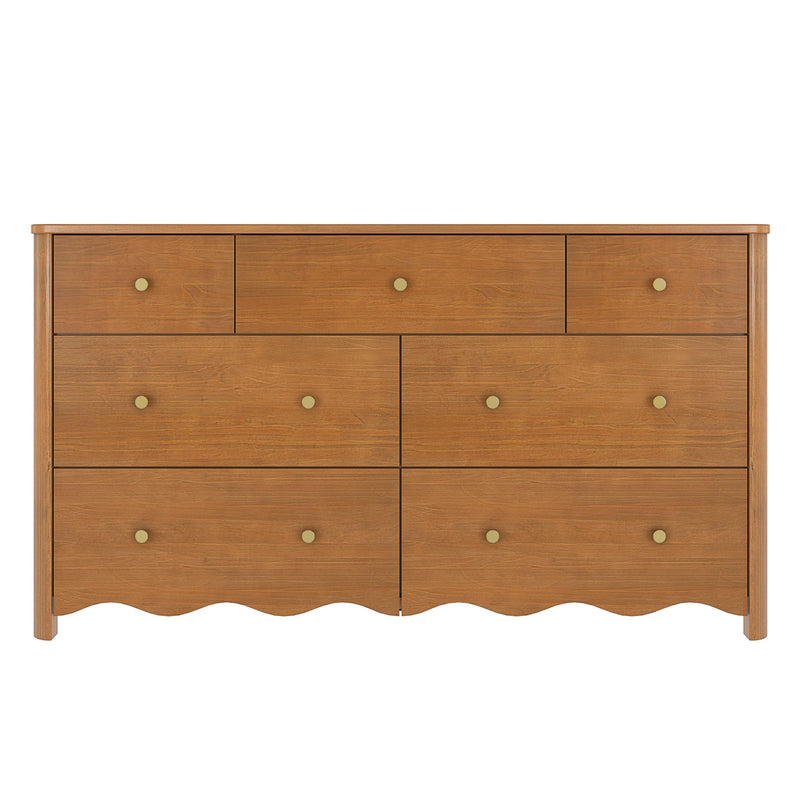Warm oak-finish wooden dresser with multiple drawers, round brass knobs and scalloped apron, mid-century modern bedroom storage chest