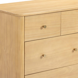 Close-up of light maple dresser with smooth rounded top edge and brass cone knobs, modern minimalist chest of drawers