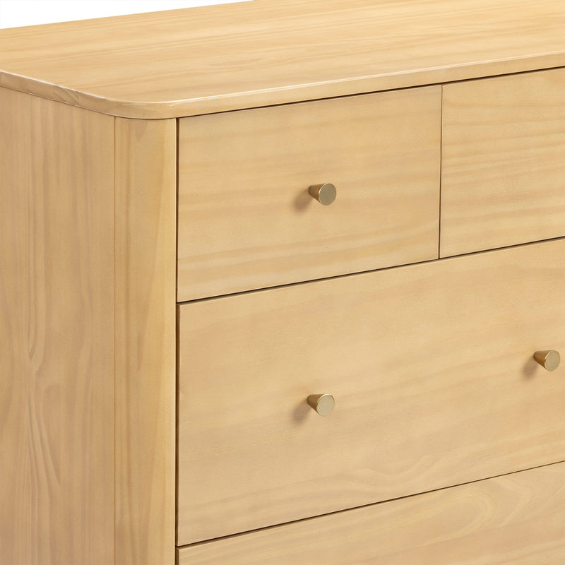 Close-up of light maple dresser with smooth rounded top edge and brass cone knobs, modern minimalist chest of drawers